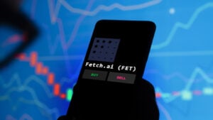 Fetch.AI (FET) cryptographic logo displayed on a smartphone with words 