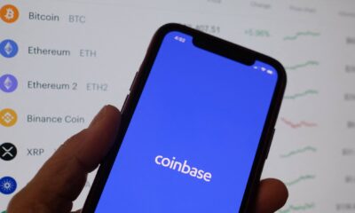 Coinbase's logo on a phone in front of crypto prices